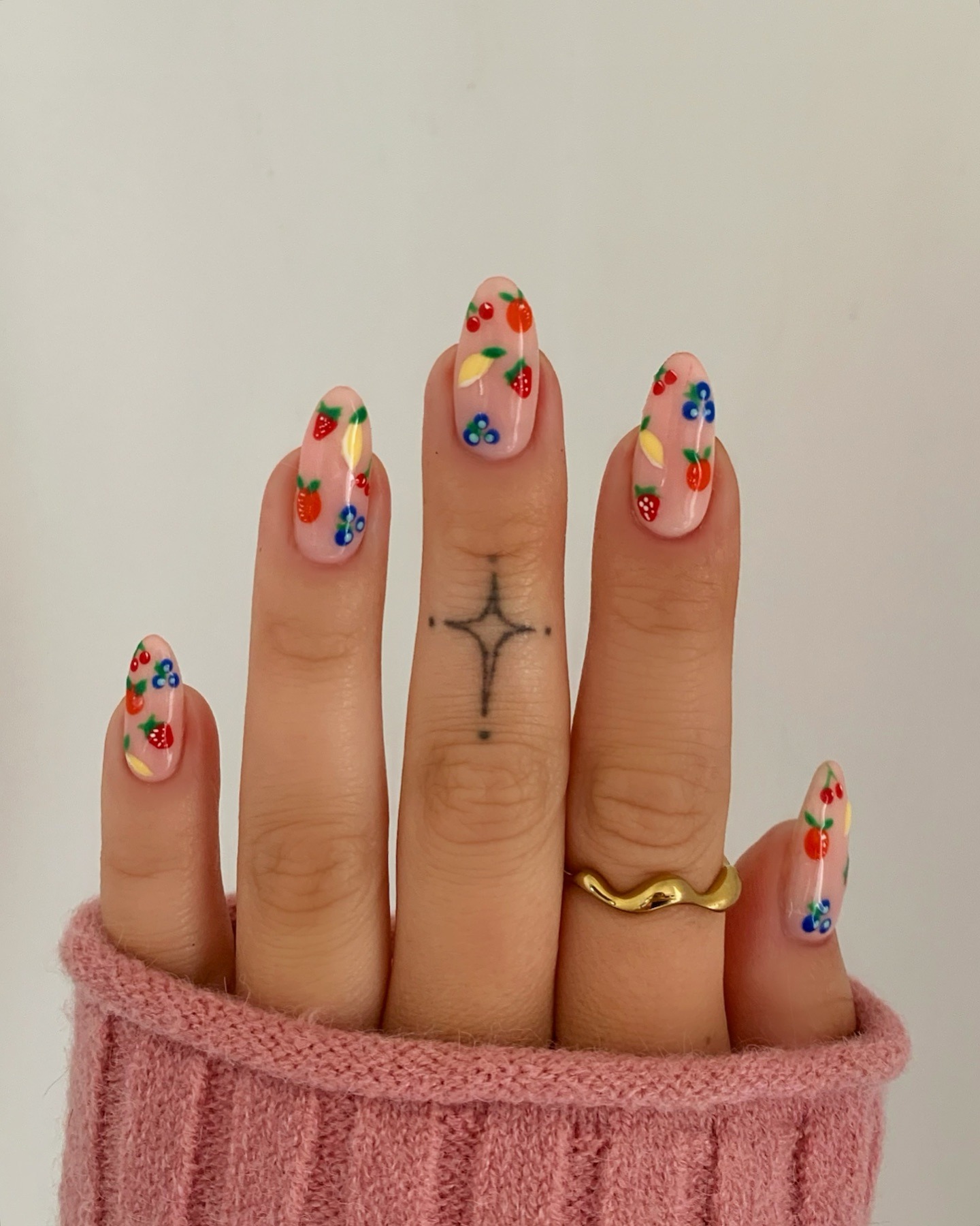 Long, almond nails with fruit painted on them.