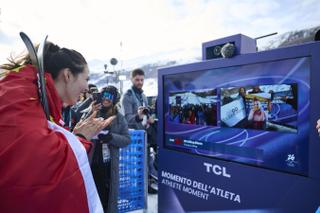 Athlete talking to a TCL display showing other athletes at the Winter Olympics