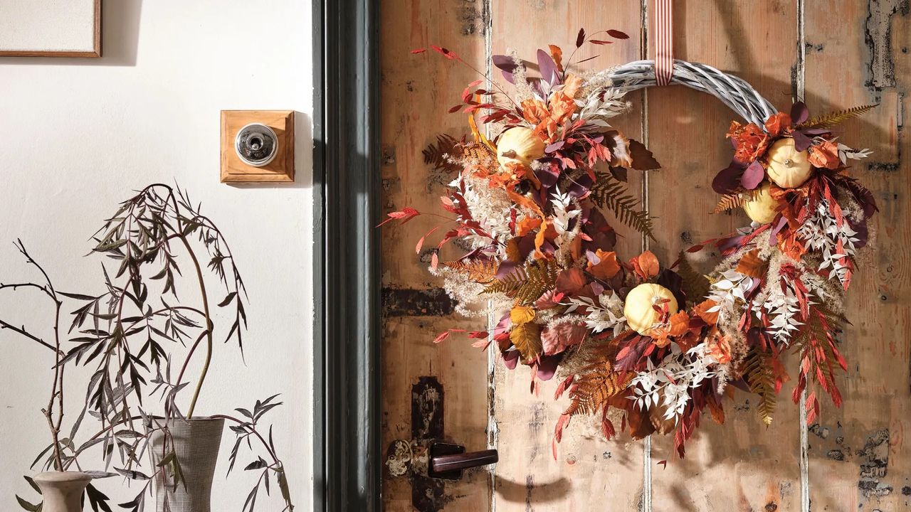 an autumnal wreath made from dried flowers and gasses and tiny pumpkins