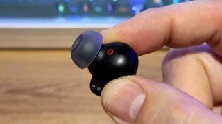 LG Tone Free T90S earbud held up between thumb and index finger.