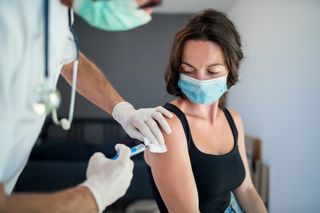 Coronavirus vaccine side effects: Woman with face mask getting vaccinated, coronavirus concept