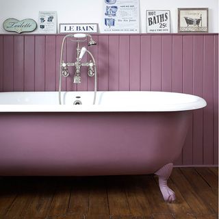 bathroom with pink wall and pink bathtub and wooden floor