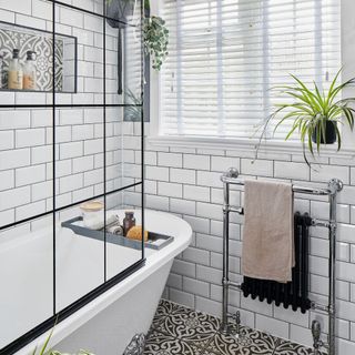 bathroom with patterned floor tiles, bath and shower screen with black lines