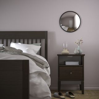 Bedroom with a convex mirror with a black frame above the nightstand