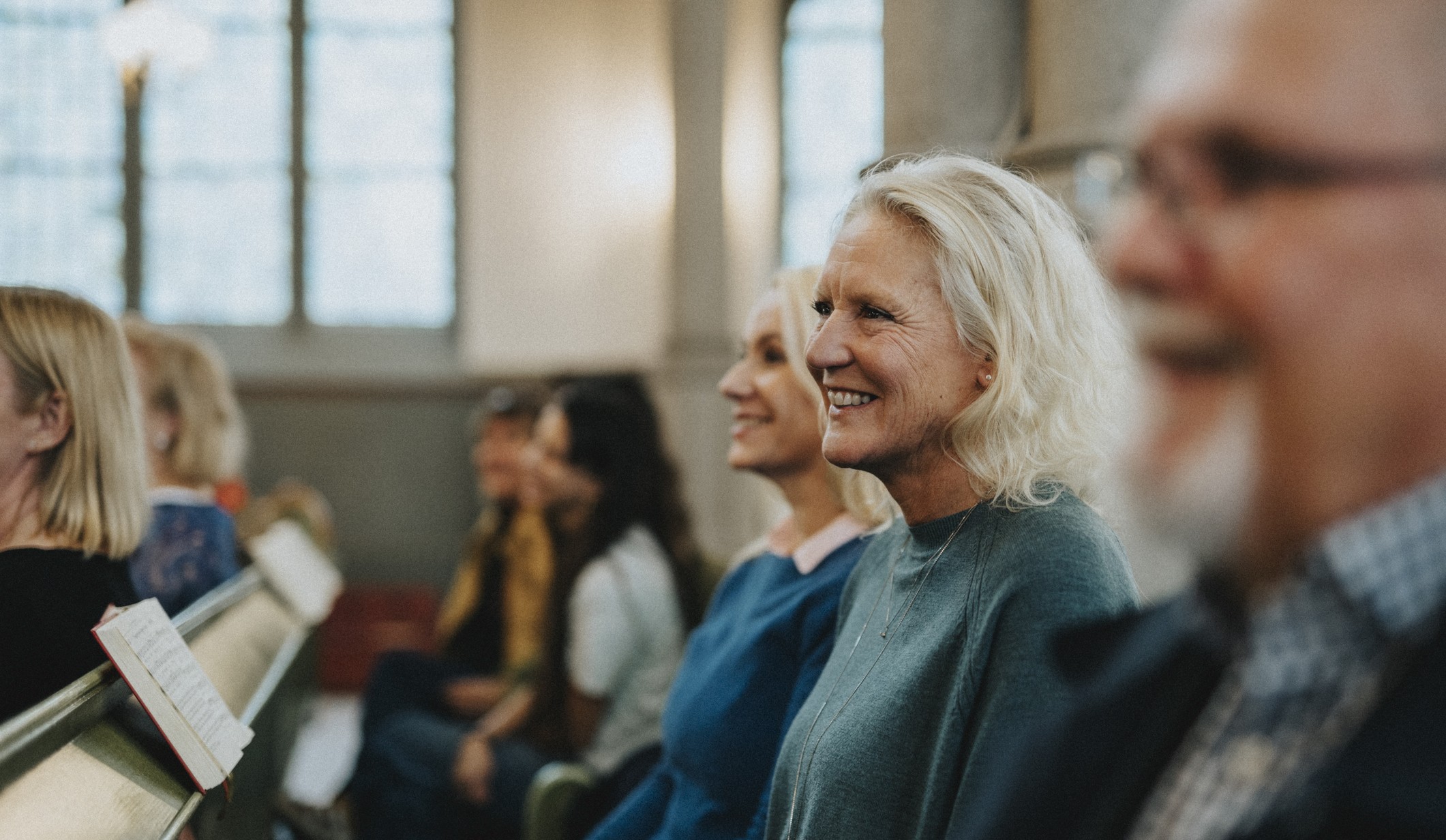A smiling older couple sits next to their adult daughter during a church service.