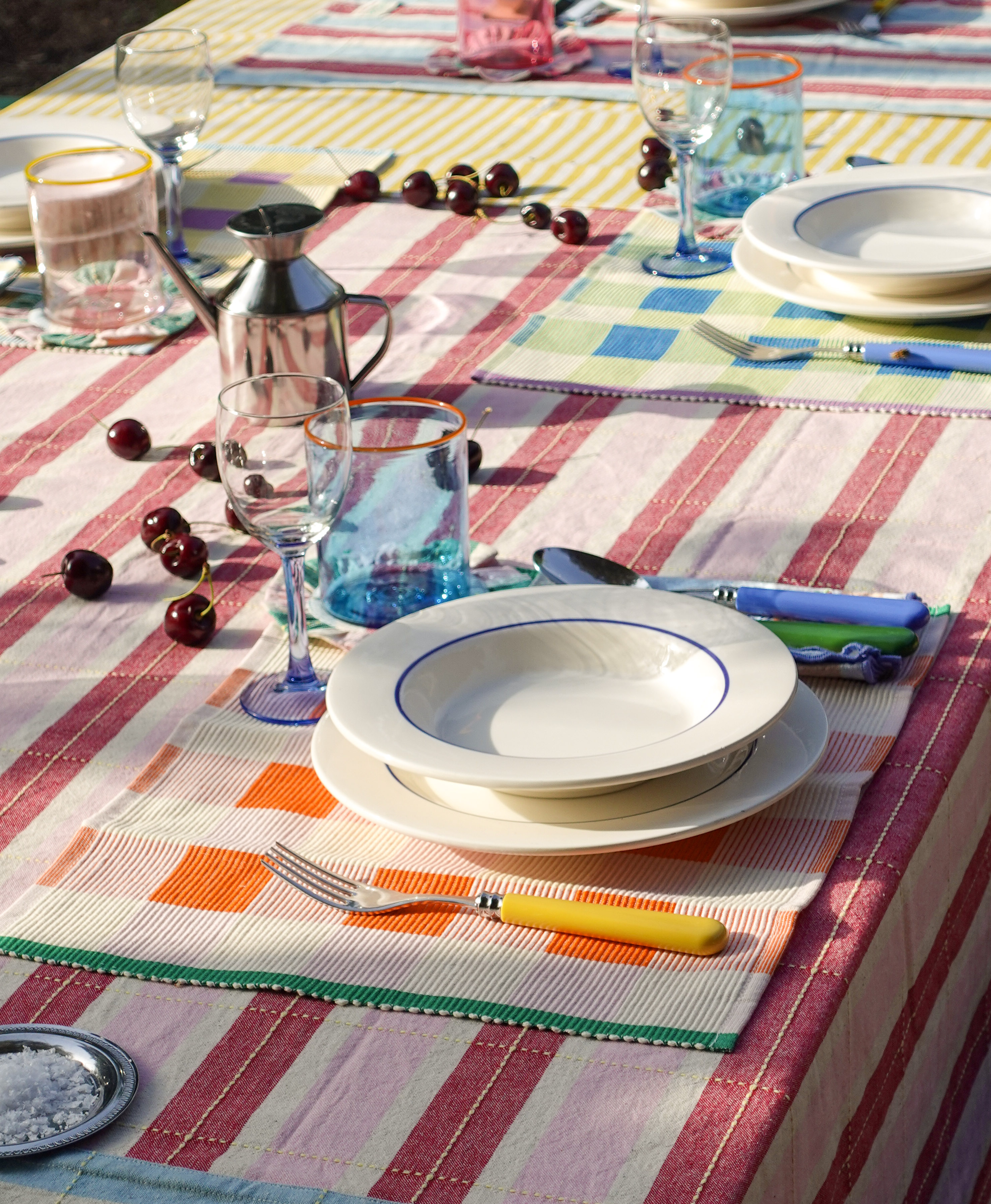 Close-up pictures of beautifully laid tables with plenty of food, colorful candles, serveware, and striped table cloths, vintage details, and pool views.