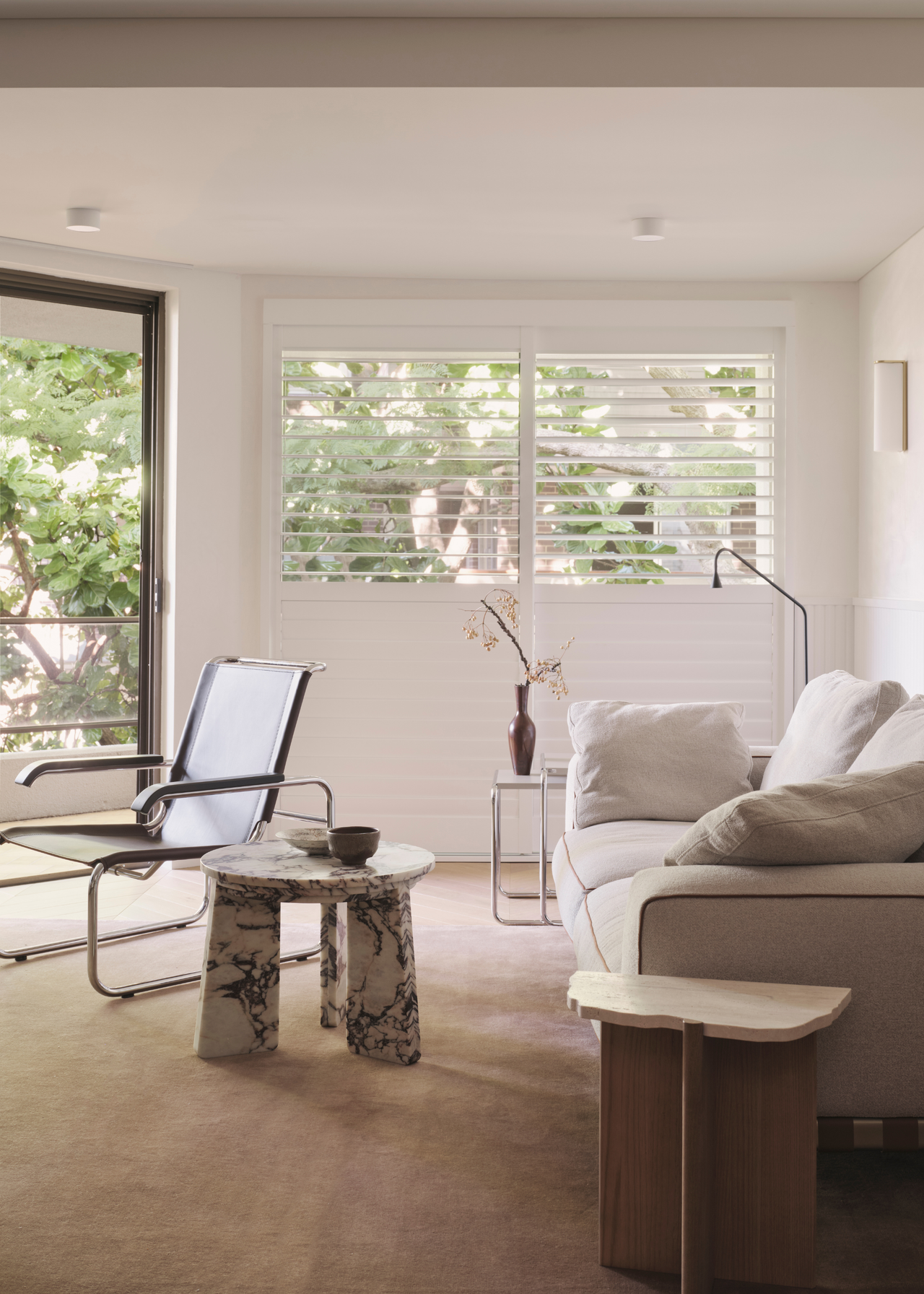 light airy living room with white sofa, marble side table and a leather side chair