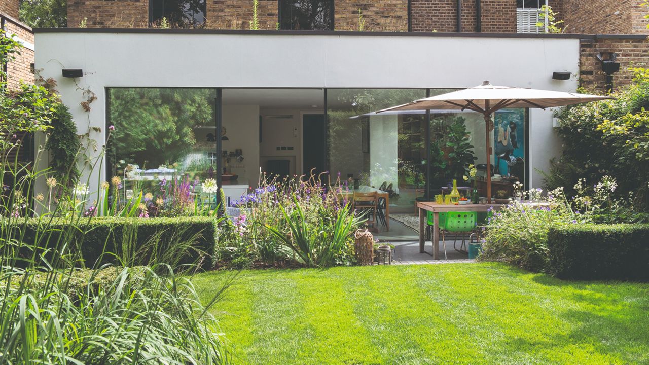 A back garden with a green lawn and garden furniture set