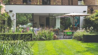 A back garden with a green lawn and garden furniture set