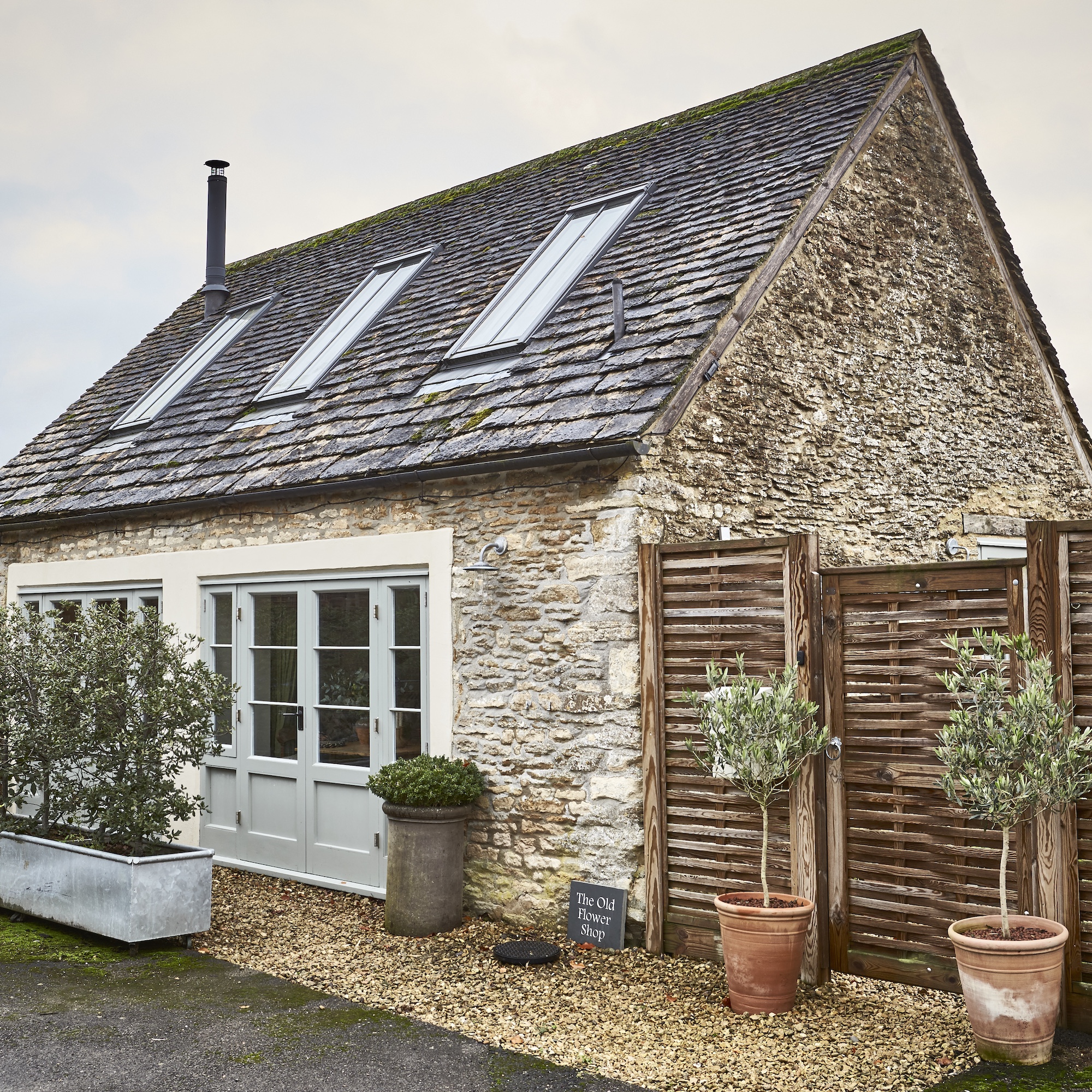 exterior of small stone cottage with french doors and roof windows