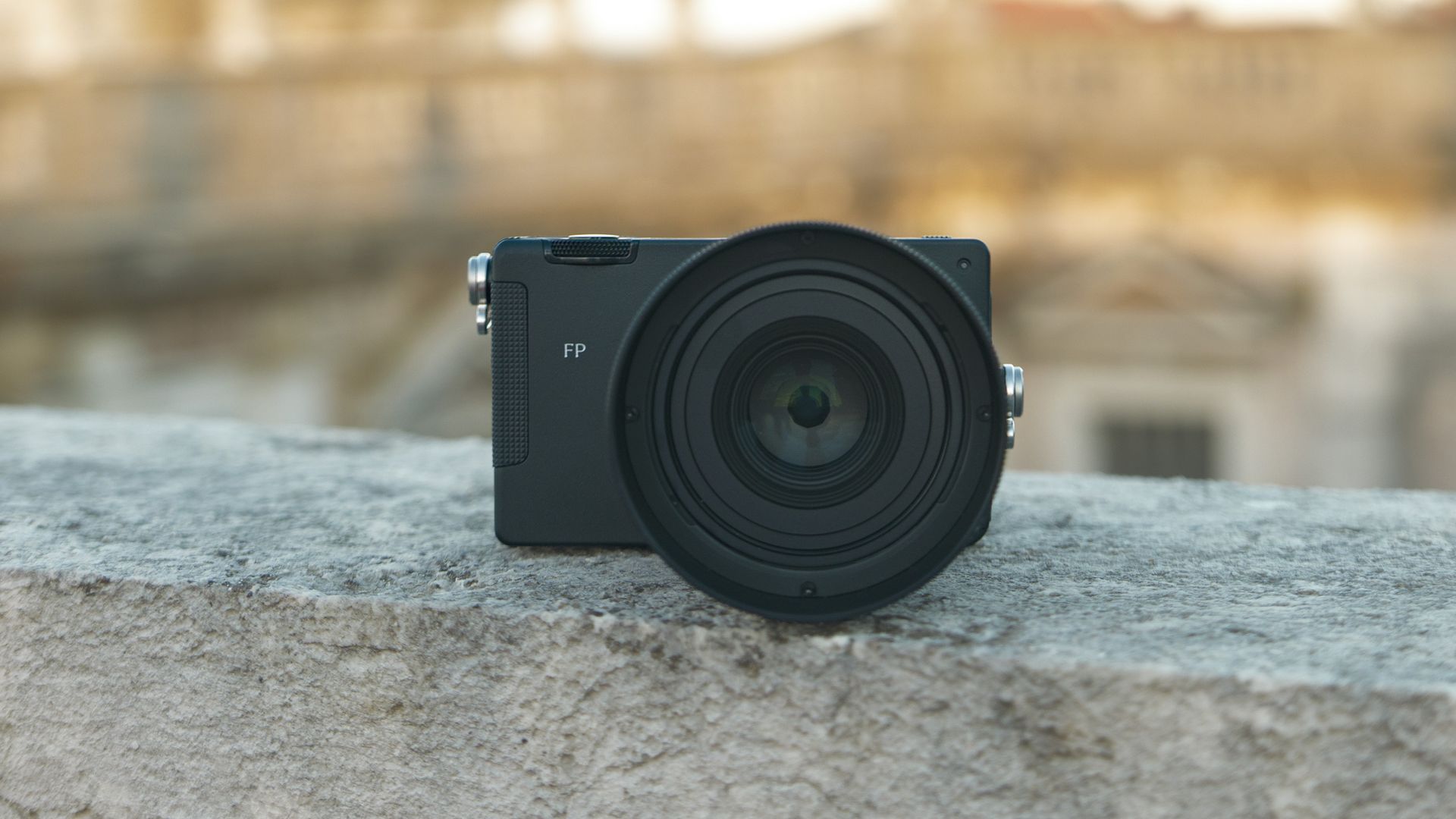 Sigma FP2 mirrorless camera with the 50mm f/2 contemporary lens attached, placed on a marble wall, at golden hour
