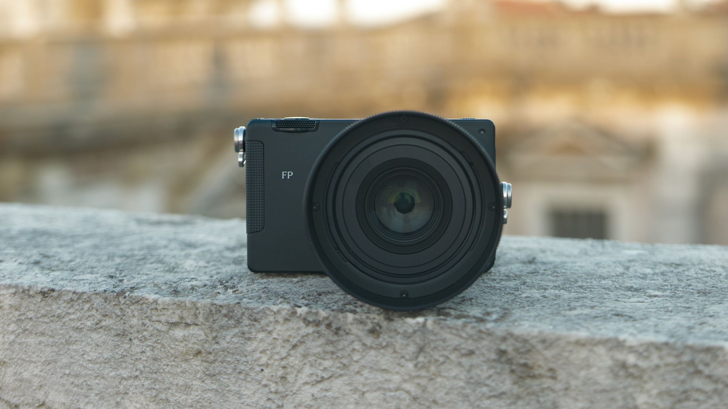 Sigma FP2 mirrorless camera with the 50mm f/2 contemporary lens attached, placed on a marble wall, at golden hour