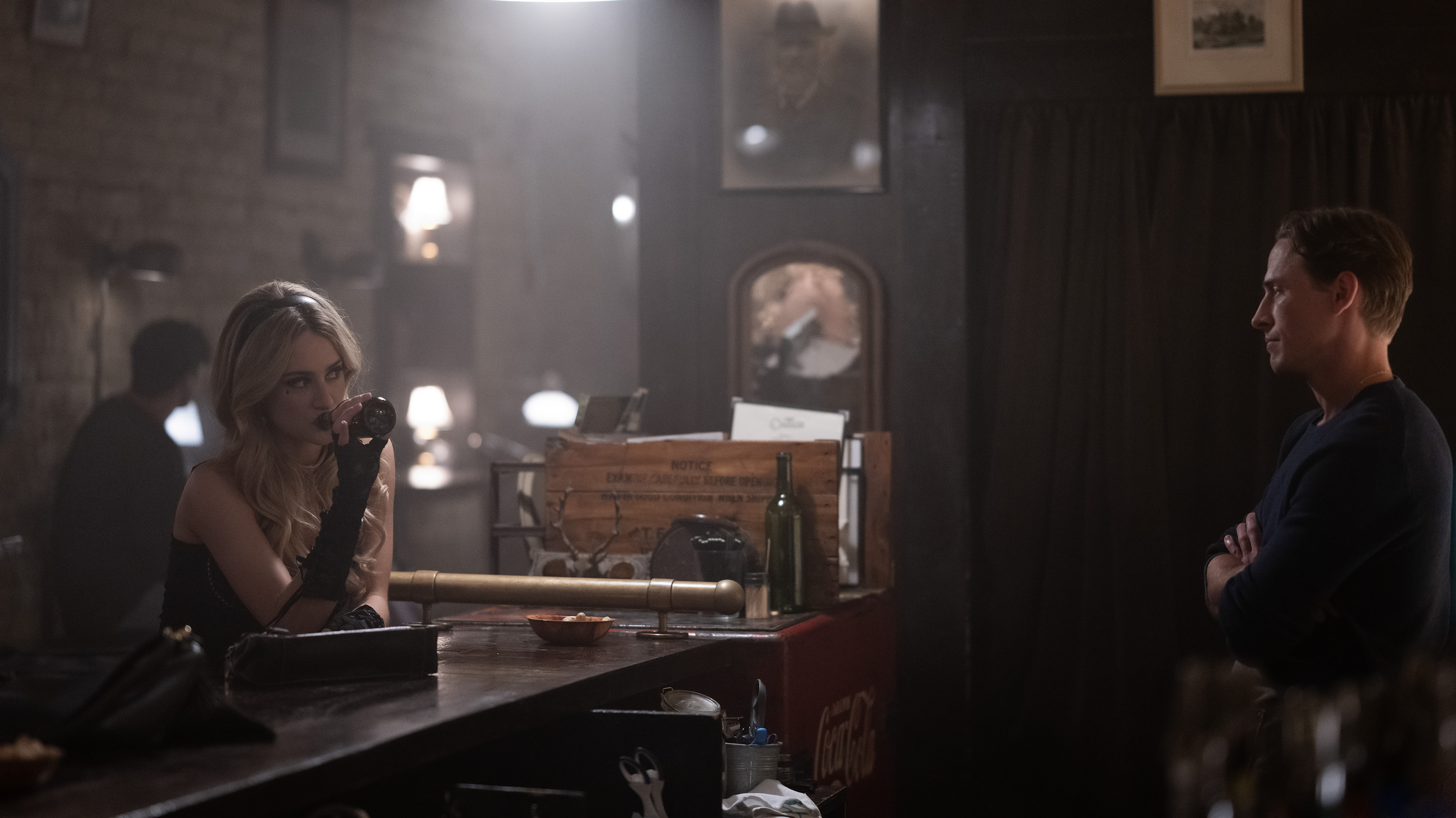 grace van patten as lucy wearing formal wear and long gloves talking to a bartender played by edmund donovan over a bar in tell me lies season 3