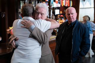 Billy Mitchell and Stevie Mitchell hugging as Phil Mitchell stands behind them unimpressed.