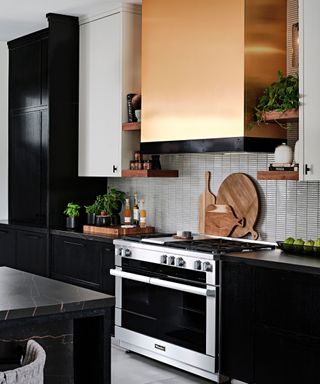 A kitchen with dark cabinetry and a bright copper range hood