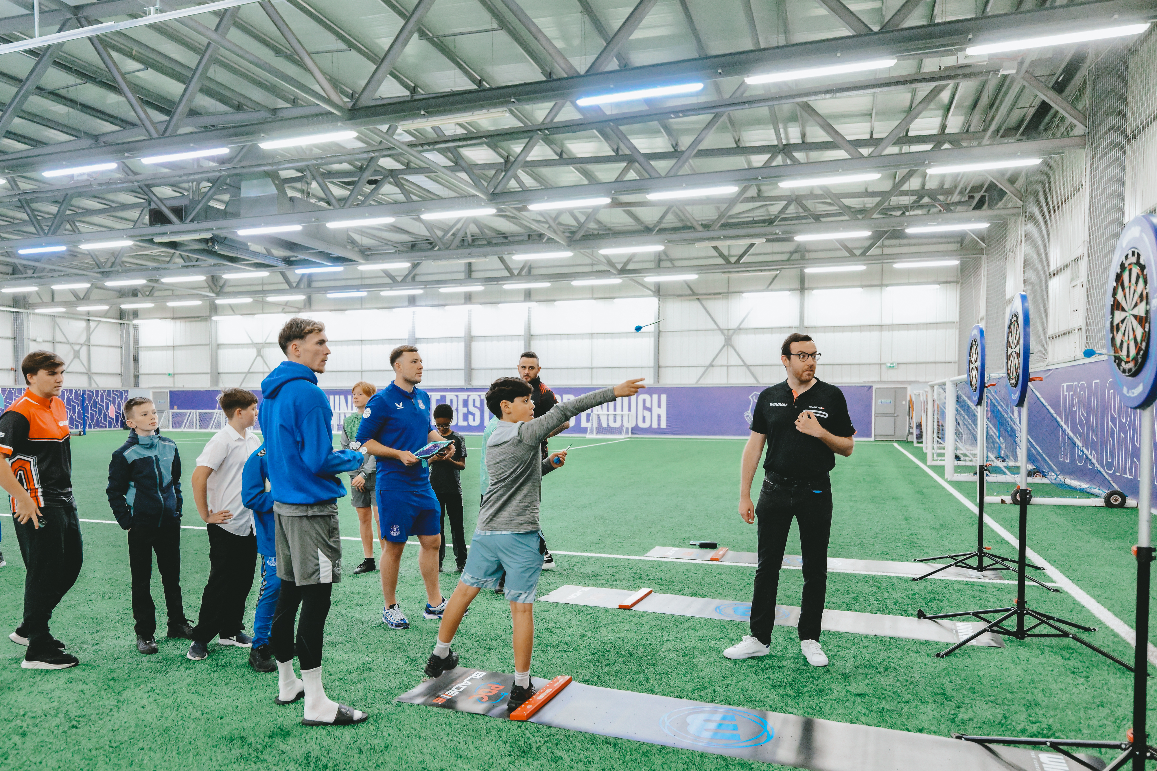 James Garner plays darts with Everton fans at Finch Farm during an Everton in the Community event