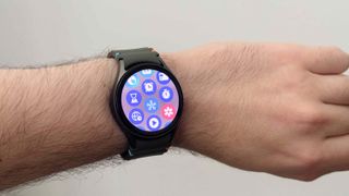 The Samsung Galaxy Watch 7 worn on someone's wrist, displaying apps on the home screen.