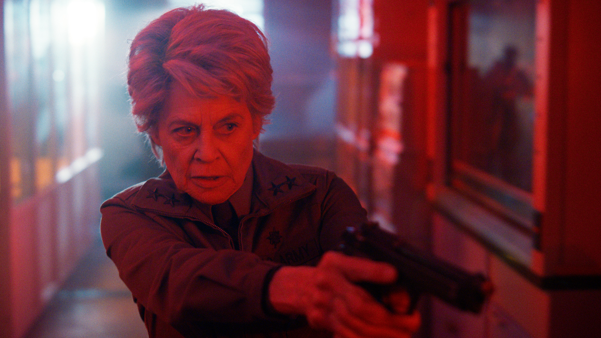 Doctor Kay lit up by a red light and holding a handgun in Stranger Things season 5