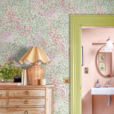 Floral wallpaper with green door frame and a wooden chest of drawers