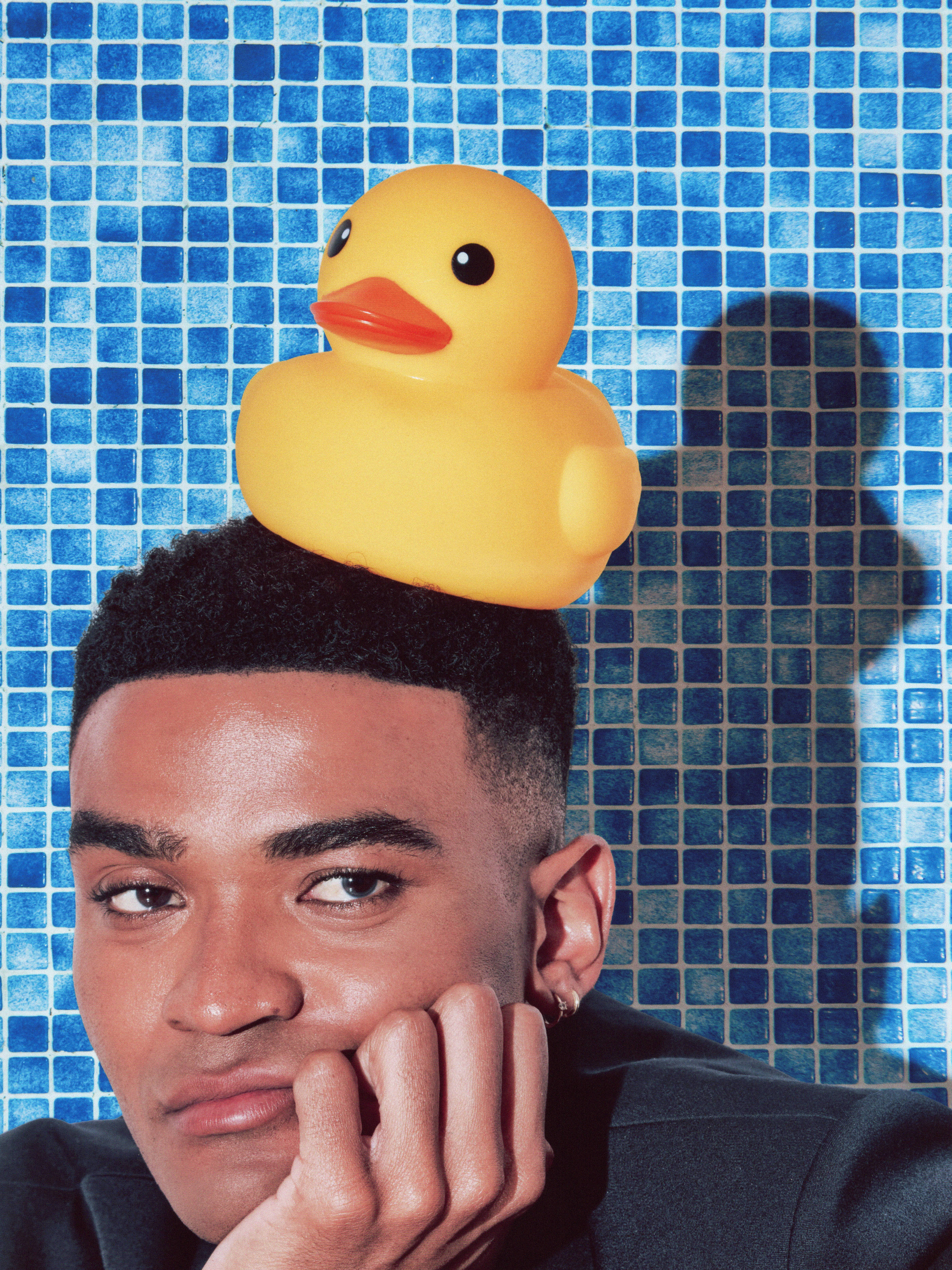 Owen Thiele poses against a blue tile backdrop with a rubber ducky on his head