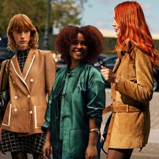 three women wearing jackets, two with tan, one with green, with red hair