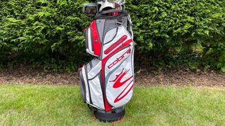The Red and white Cobra Ultralight Trolley Bag resting on the golf course