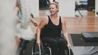 Woman in a wheelchair smiling at the gym