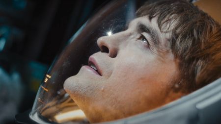 Robert Pattinson looks up at the sun in his space suit in Mickey 17.