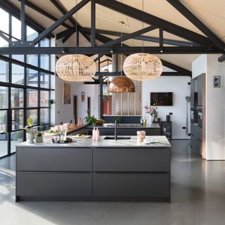Large open plan kitchen with exposed beams and brick walls