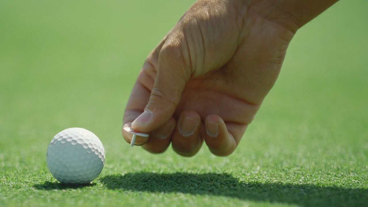 Golfer marking his ball on the green GettyImages-73974030