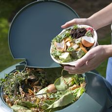 Adding kitchen scraps to compost bin