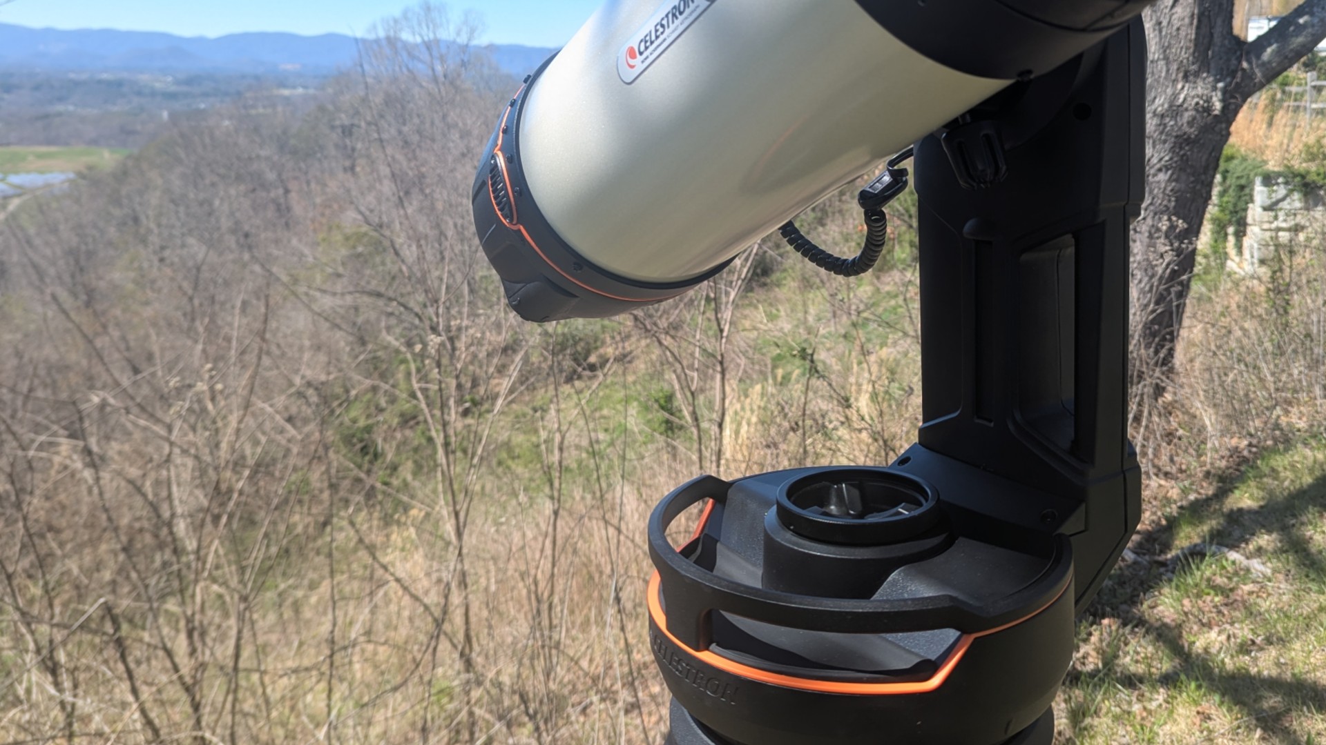 a white telescope on a grassy mountaintop under a clear blue sky