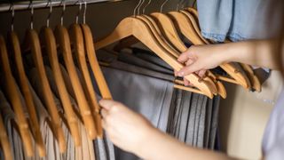 Looking through pants hung in closet