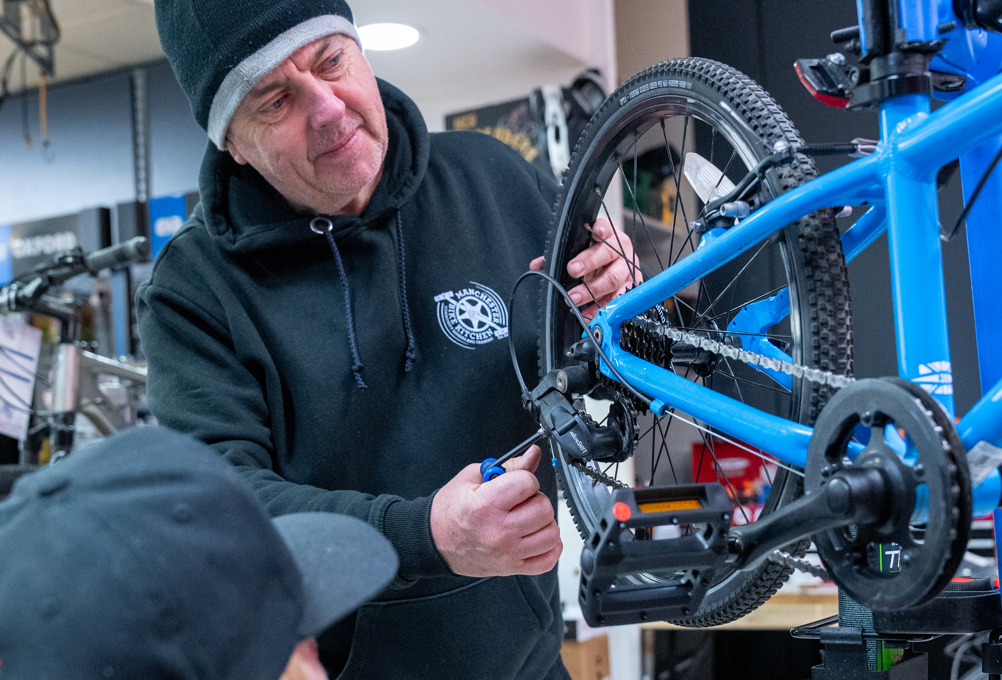 A mechanic in the Manchester Bike Kitchen repairs a kid's bike