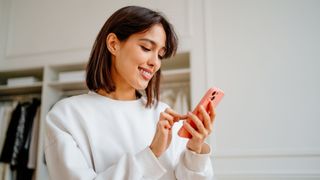 Woman looking at animal videos on phone, laughing and smiling