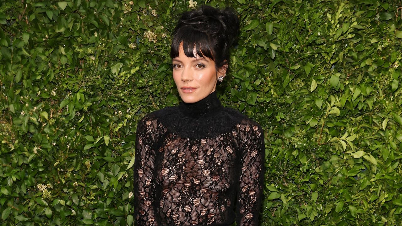 Lily Allen&#039;s design tip is so clever. Here is the singer wearing a black lace dress with her hair in a black top-knot, with a green leafy background behind her