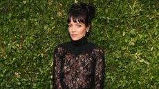 Lily Allen's design tip is so clever. Here is the singer wearing a black lace dress with her hair in a black top-knot, with a green leafy background behind her
