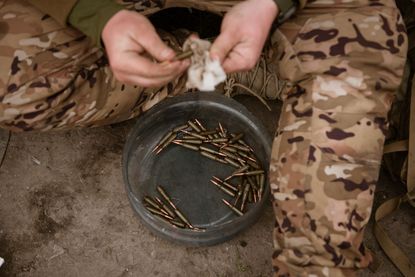 Ukrainian soldier cleans mud from bullets in Bakhmut