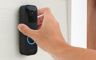 Hand pressing Blink video doorbell