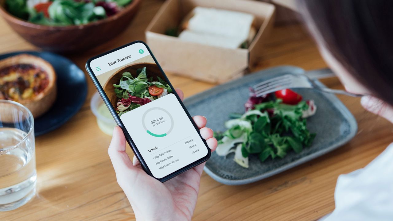 Person measuring out calories on phone app