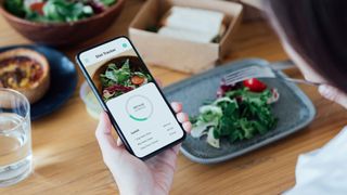 Person measuring out calories on phone app