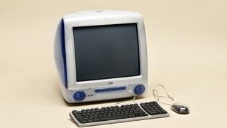 Apple iMac G3 computer from 1998 in original Indigo blue color with mouse and keyboard isolated on beige background