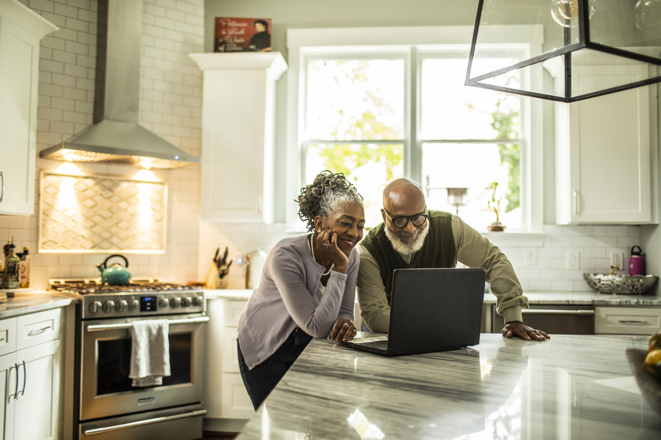 a happy couple sitting in their kitchen on a video call
