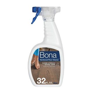 A white plastic spray bottle with a blue trigger. A brown wood floor on the label with Bona branding.