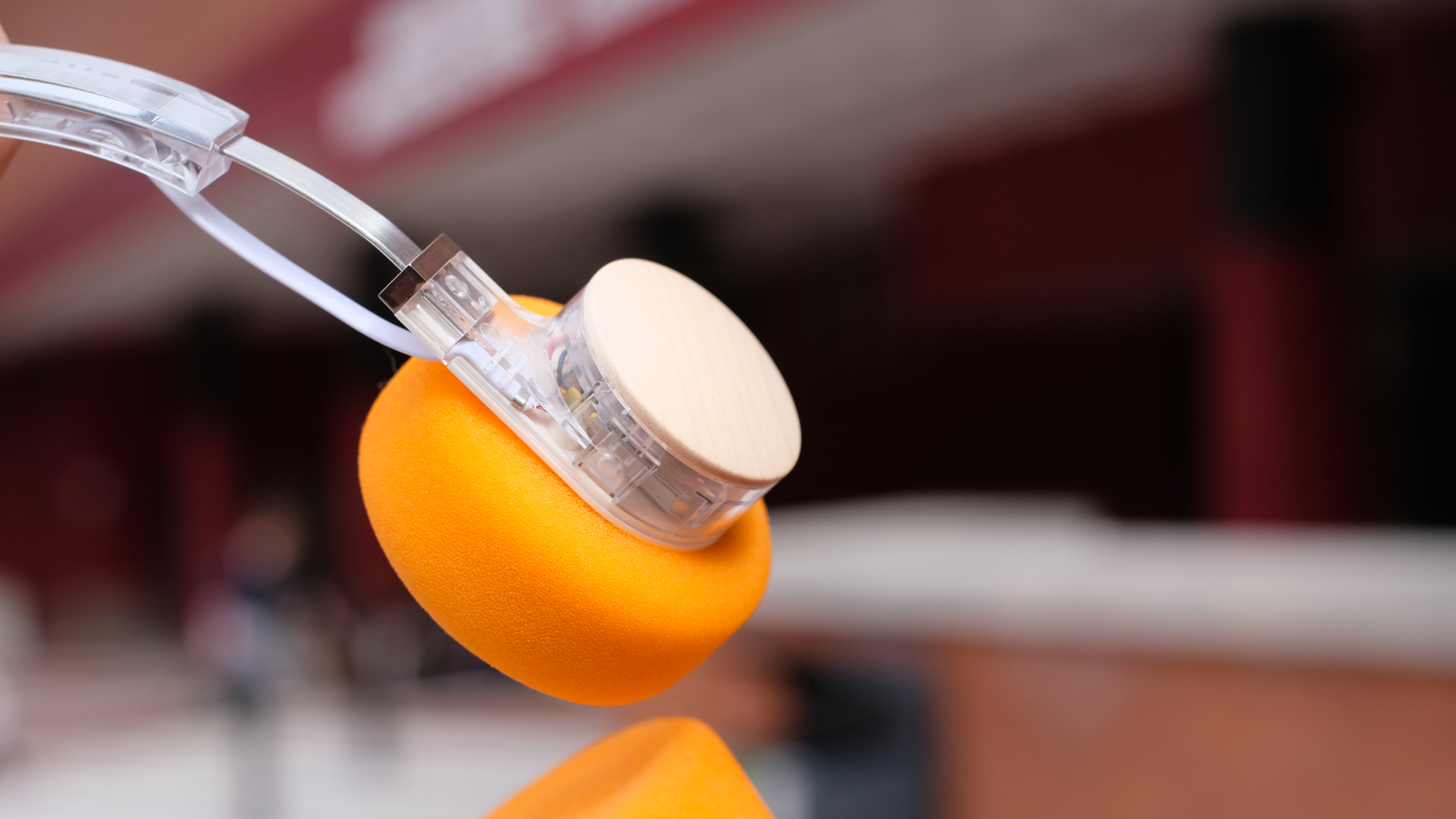 A photograph of the FiiO EH11 over-ear headphones with a transparent frame and orange foam earpads.