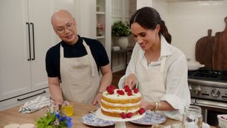 Daniel Martin and Meghan, Duchess of Sussex cut a cake.