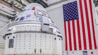 a cone-shaped spacecraft in front of an american flag in a warehouse