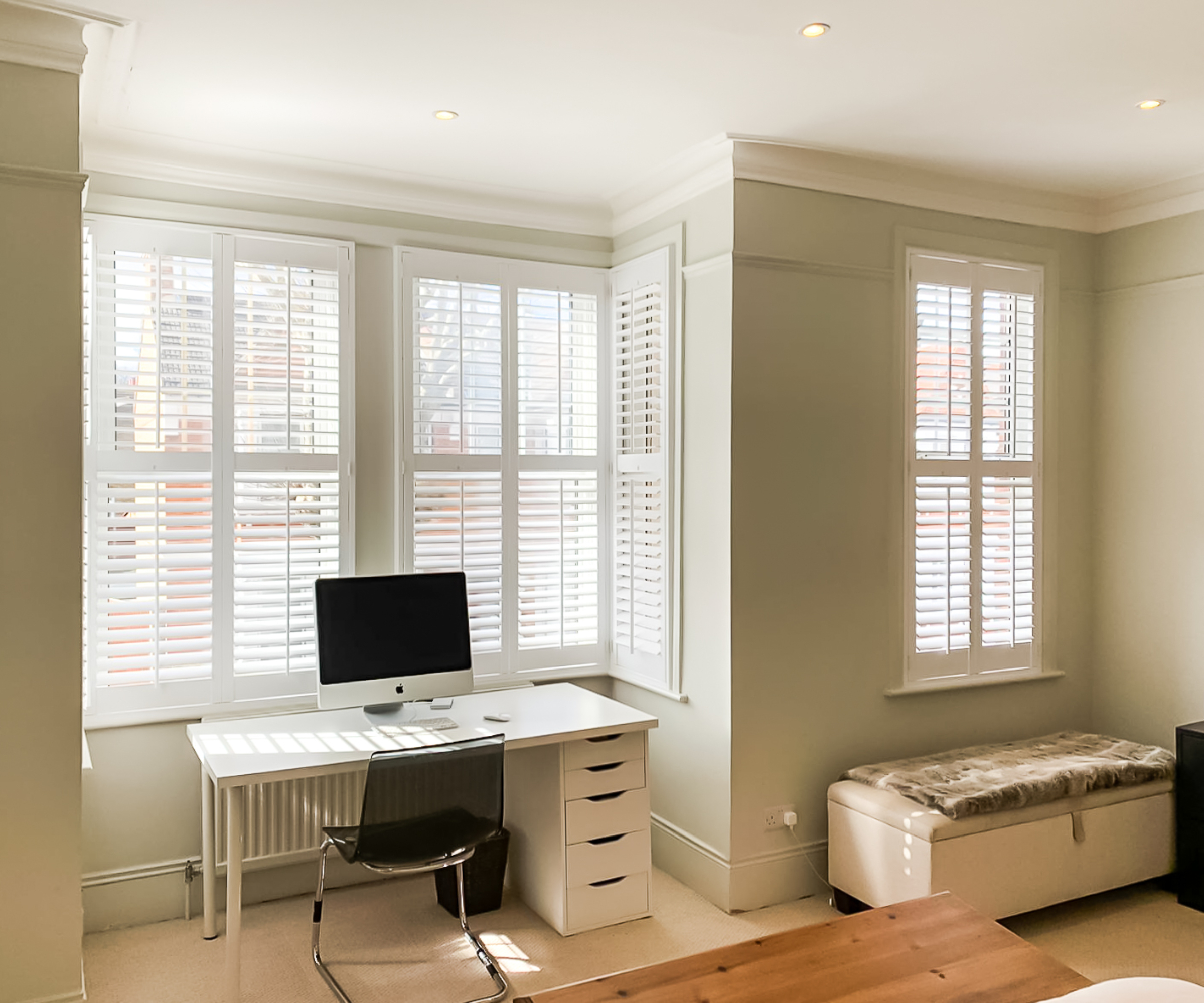 home office in window recess with white shutters on windows