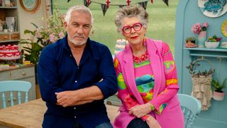 Paul Hollywood in a dark shirt and Prue Leith in a pink tunic and patterned top in the tent in The Great British Bake Off 2025