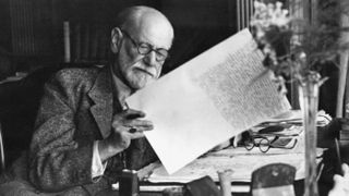 Sigmund Freud, 1856-1939, Austrian neurologist, in the office of his Vienna home looking at a manuscript.